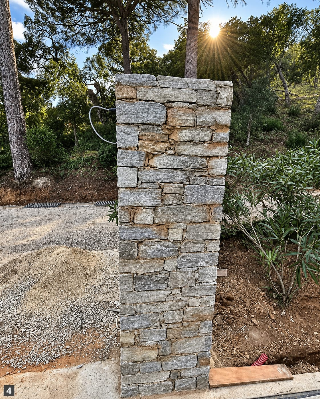 Pilier en pierre naturelle terminé, à contre-jour sous les pins